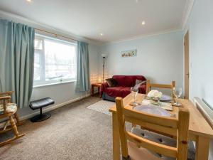 a living room with a table and a red couch at The Annexe At Whitfield in Saint Margaretʼs at Cliffe