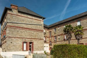 ein altes Backsteingebäude mit einer Palme in der Unterkunft La Castine in Saint-Cast-le-Guildo