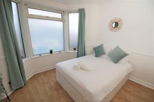 een slaapkamer met een wit bed en een raam bij Large Modern House by Property Promise in Cardiff