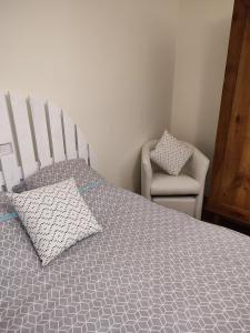 a bedroom with a large bed and a chair at chambre d'hôtes chez DENFLO in Sevremont