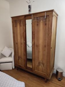 a wooden cabinet with a mirror in a bedroom at chambre d'hôtes chez DENFLO in Sevremont