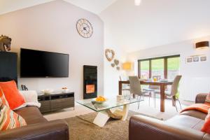 a living room with a flat screen tv and a table at Coomb View at Sandbeds in Kendal