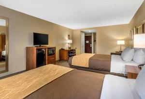 a hotel room with two beds and a flat screen tv at Comfort Inn & Suites Peachtree Corners in Norcross