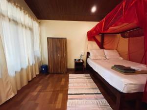 a bedroom with a bed with a red canopy at Jardim a Mar in Agonda