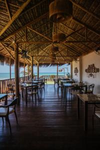 an empty restaurant with tables and chairs and the ocean at Hurricane Jeri in Jericoacoara