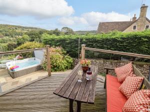 a wooden deck with a table and a bath tub at The Gables in Stroud