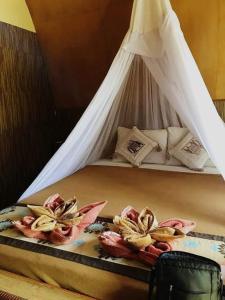 un letto con baldacchino bianco e fiori di Meno Turtle BUNGALOWS a Gili Meno