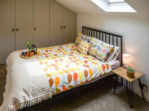 een slaapkamer met een bed en een tafel met een sprei bij Dove Cottage in Knaresborough