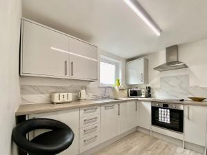 uma cozinha com armários brancos e uma cadeira preta em Station Suite 1 - Uk40737 em North Tidworth