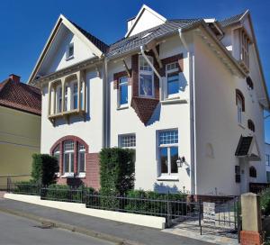 a white house with a fence in front of it at VILLA EMMILIO einzigartiges City Apartement 73 qm in Bad Oeynhausen