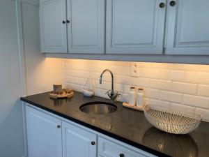a kitchen counter with a sink and white cabinets at Villa Emilia in De Haan