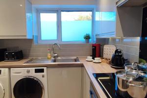uma cozinha com uma máquina de lavar roupa e um lavatório em Comfortable 1 Bed flat with Air Con em Borehamwood