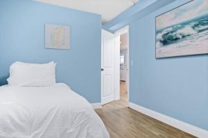 une chambre bleue avec un lit et un tableau mural dans l'établissement Gammys Beach Bungalow, à Ventnor City
