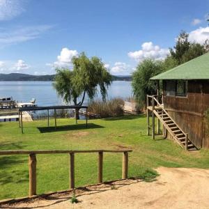 a park with a fence and a house and a lake at Maravillosa cabaña en orilla de Lago Vichuquén 