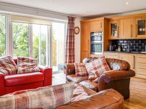 a living room with two couches and a kitchen at Mount Farm - The Stable in Harker