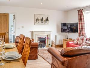 a living room with couches and a table and a fireplace at Mount Farm - The Stable in Harker