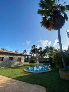 a swimming pool in a yard with a palm tree at Casa de Praia no Porto das Dunas in Aquiraz