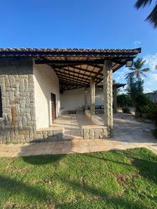 a stone building with a wooden pergola at Casa de Praia no Porto das Dunas in Aquiraz