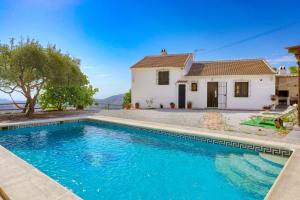 a villa with a swimming pool in front of a house at Cortijo Montes I in Cómpeta