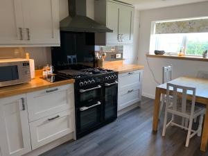 a kitchen with a black stove and a table at Sighthill Cottage, North Tolsta in Stornoway