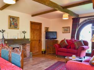 a living room with red furniture and a fireplace at Acorn Barn in Foggathorpe