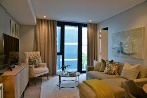 35 On Main by Stay In Luxury في كيب تاون: غرفة معيشة مع أريكة وكراسي وتلفزيون