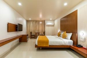 a hotel room with a bed and a television at Pai Resort in Belgaum