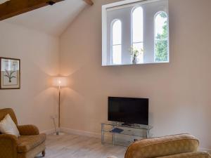 a living room with a flat screen tv and two chairs at Hen House in binbrook