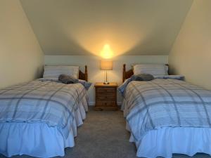 um quarto com 2 camas e um candeeiro numa mesa de cabeceira em Sighthill Cottage, North Tolsta em Stornoway