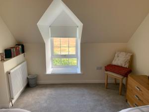 Zimmer im Dachgeschoss mit einem Fenster und einem Stuhl in der Unterkunft Sighthill Cottage, North Tolsta in Stornoway