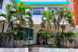 una valla con palmeras frente a una casa en Puerta Aqua by La Puerta Hostels en Santa Marta