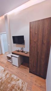 a room with a desk with a television and a large wooden cabinet at Vila Casablanca - Boutique Hotel & Restaurant in Shkodër