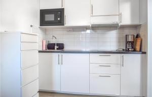 a white kitchen with white cabinets and a microwave at Nice Apartment In Frjestaden With Kitchen in Färjestaden