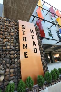 a sign in front of a building with plants at Stone Head Hua Hin in Hua Hin