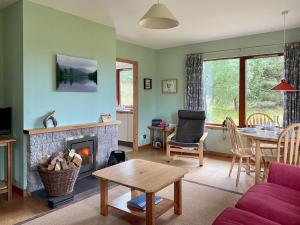 a living room with a fireplace and a table at Kintulloch in Insh