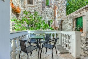 a balcony with chairs and a table and an umbrella at Old stone house St Lawrence in the heart of Sibenik's old town in Šibenik