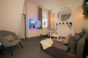 ein Wohnzimmer mit einem Sofa, Stühlen und einem Spiegel in der Unterkunft Fitzroy Terrace by Property Promise in Cardiff