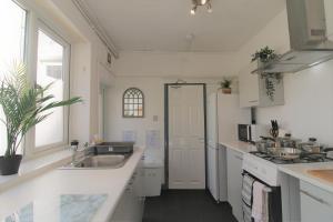 a white kitchen with a sink and a stove at Fitzroy Terrace by Property Promise in Cardiff