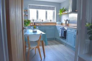 a kitchen with blue cabinets and a table with a chair at Sanderlings - Suffolk Coastal Escapes in Pakefield