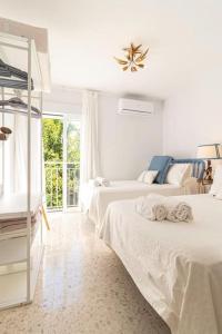 Un dormitorio blanco con dos camas y una ventana. en La Casa de los Arcos - Casco Histórico - Parking opcional, en Jerez de la Frontera