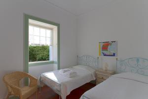 a bedroom with two beds and a table and a window at Casa da Madalena do Mar in Madalena do Mar