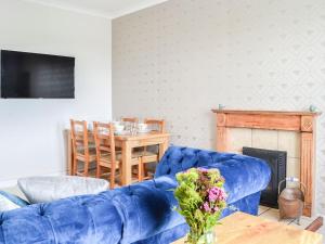 a living room with a blue couch and a table at Bogrie Country Cottage in Canonbie
