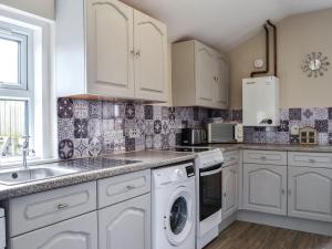 een witte keuken met een wastafel en een vaatwasser bij Bogrie Country Cottage in Canonbie