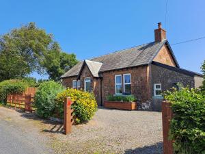 uma casa de tijolos com uma cerca em frente em Bogrie Country Cottage em Canonbie