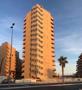 un edificio alto con una palmera frente a una calle en Apartamento Vistamar, en La Manga del Mar Menor
