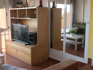 una sala de estar con un centro de entretenimiento con TV en Apartamento Vistamar, en La Manga del Mar Menor