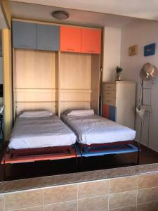 2 camas en una habitación con armarios anaranjados y azules en Apartamento Vistamar, en La Manga del Mar Menor