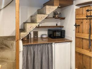 a kitchen with a counter with a microwave and a staircase at Gem Cottage in Longnor