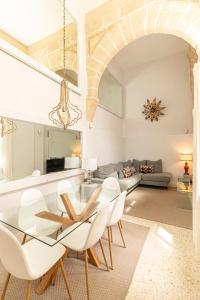 Un comedor con una mesa de cristal y sillas blancas. en La Casa de los Arcos - Casco Histórico - Parking opcional, en Jerez de la Frontera