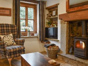 a living room with a fireplace and a tv at Gem Cottage in Longnor